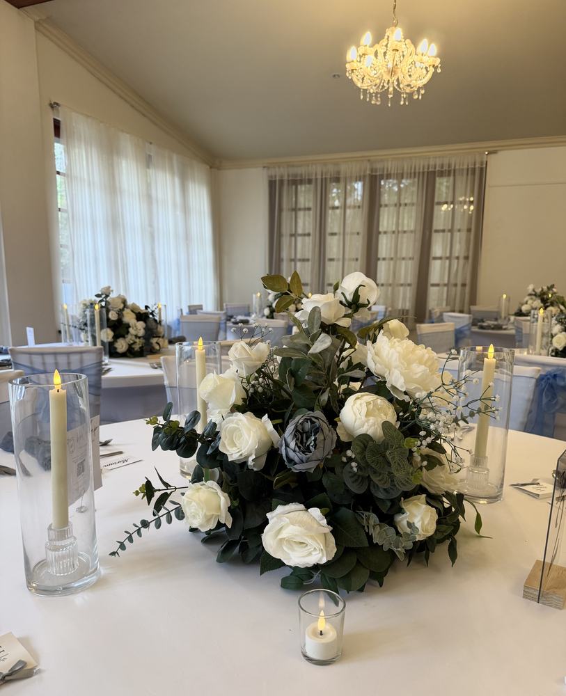A low white flower centrepiece with candles on a guest table
