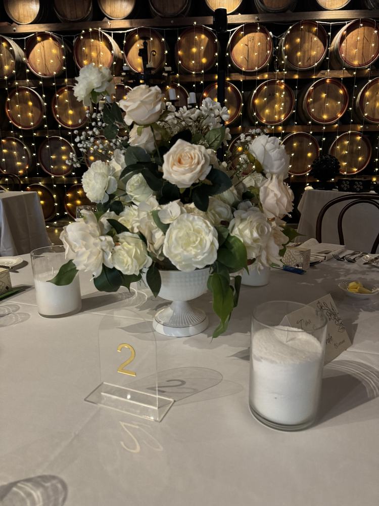 White roses in a footed bowl with a candle and an acrylic table number